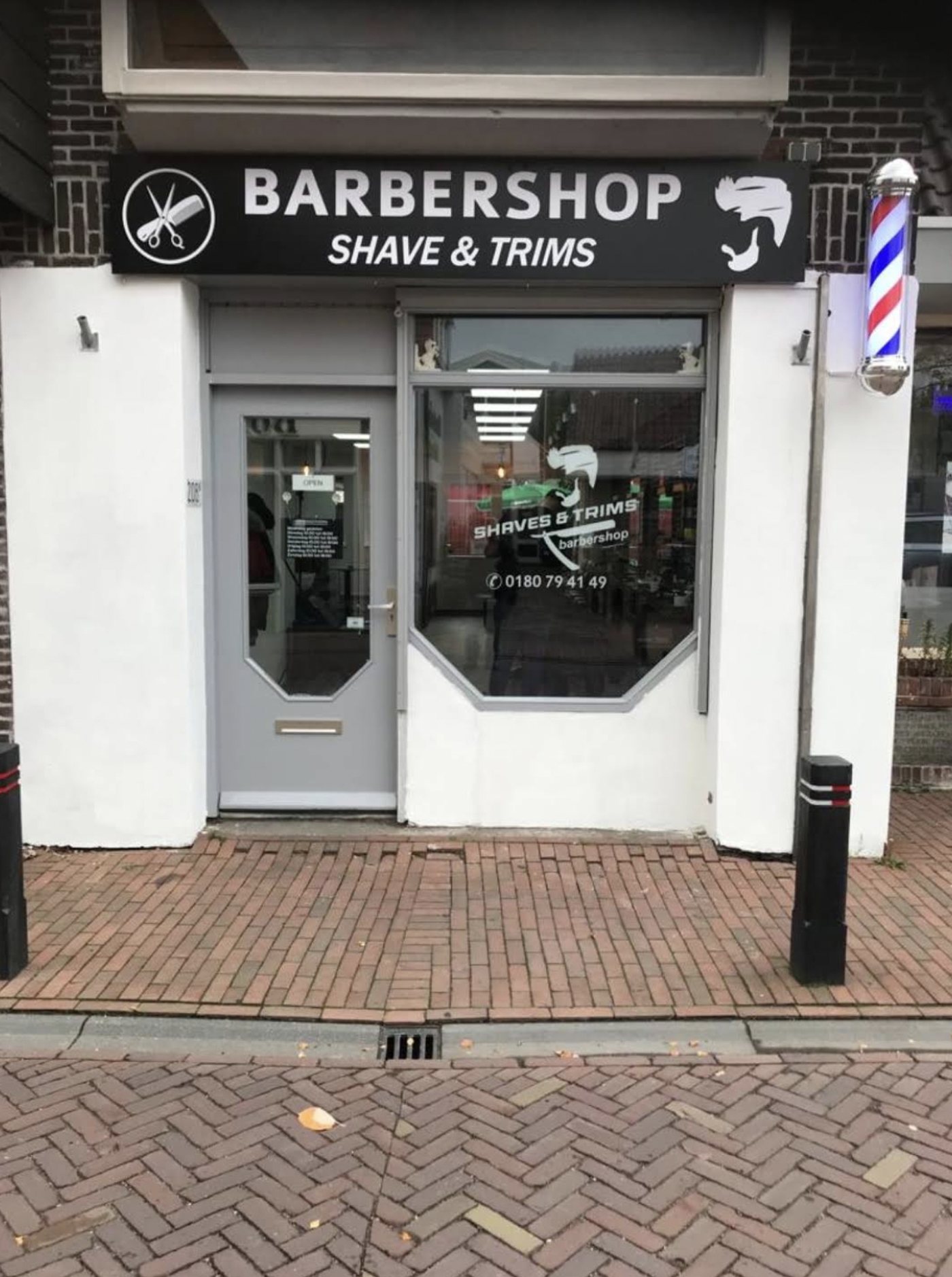 De zwarte gevel van Barbershop Shave & Trims met barberpaal aan de Dorpsstraat