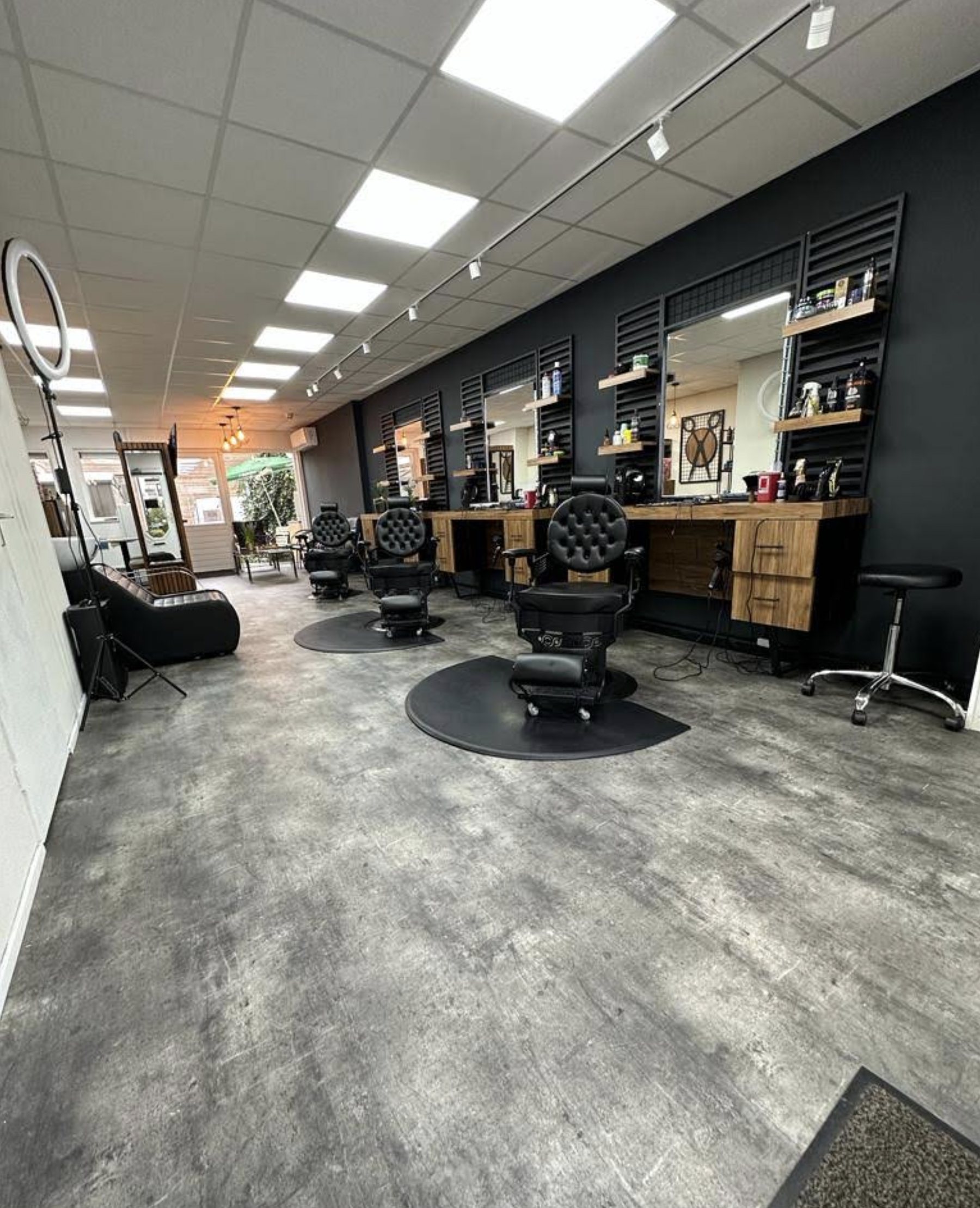 De verlichte salon van Barbershop Shaves & Trims met klassieke barberstoelen