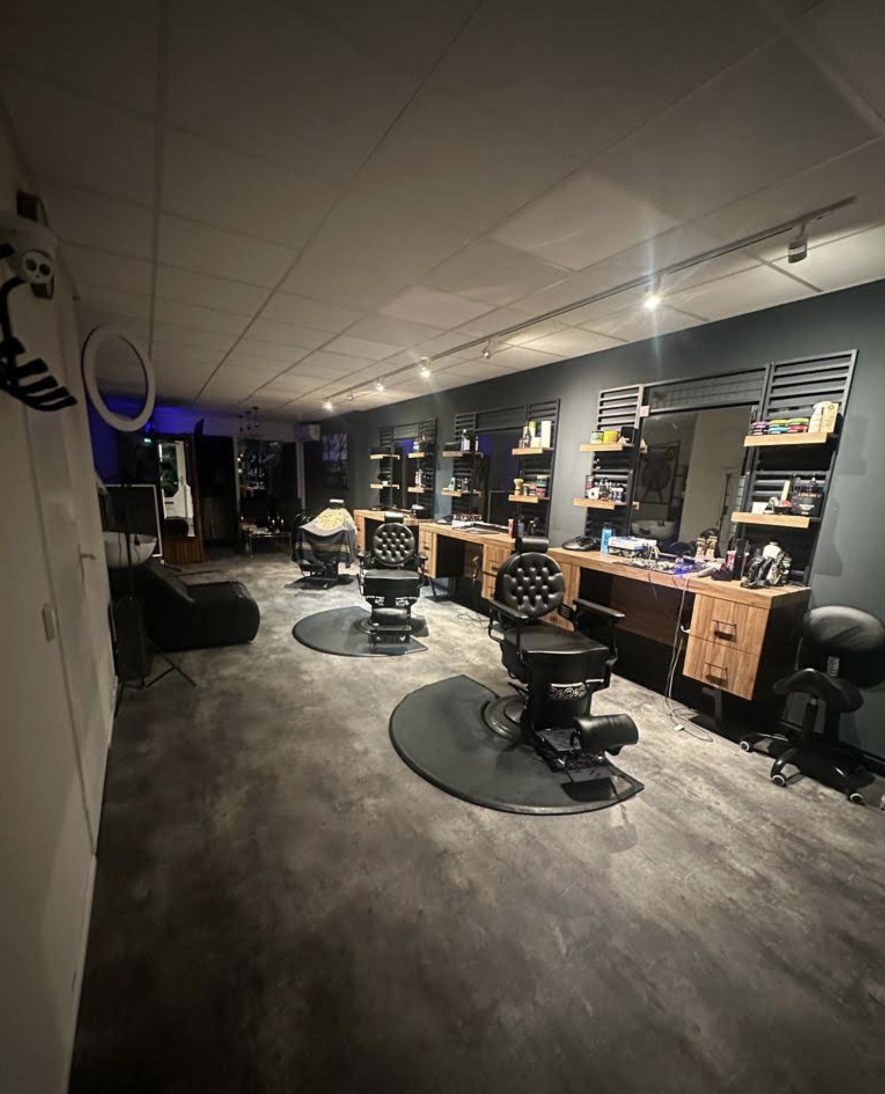 De salon bij daglicht met barberstoelen, spiegels en houten werkbladen